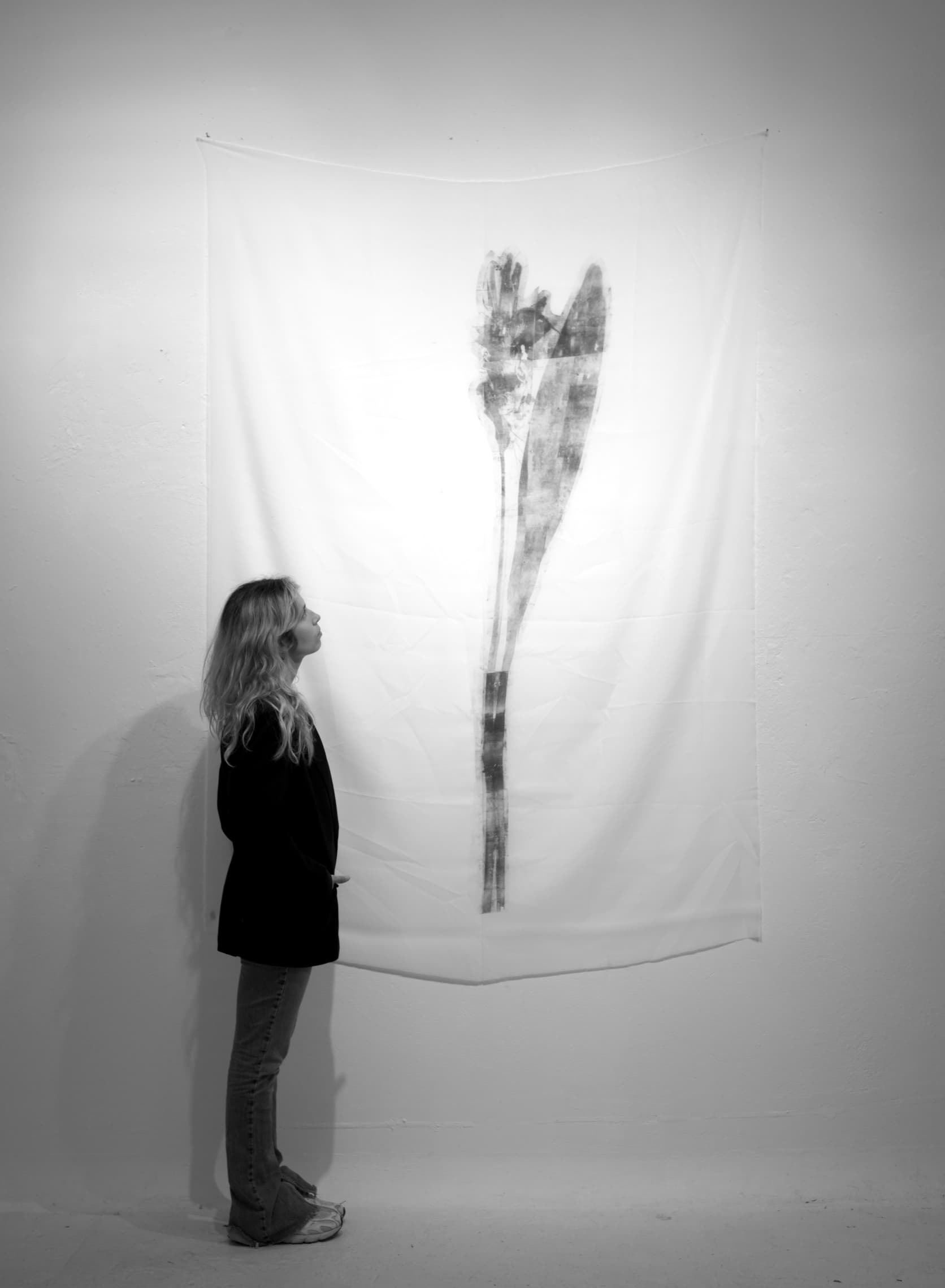 Aglaya Nogina in her Düsseldorf studio, in front of a large monochrome xerography print on textile